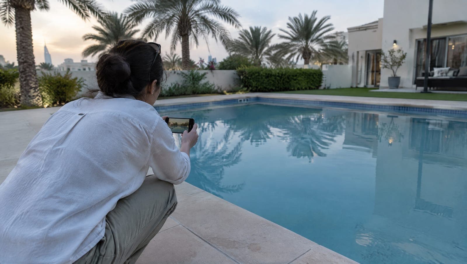 Homeowner crouching at the pool edge photographing cloudy water